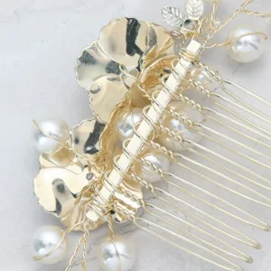 Dettaglio ravvicinato di pettine per capelli da sposa dorato con motivi floreali e perle.