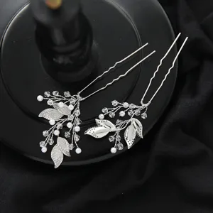 Detailed close-up of silver bridal hairpins with handmade crystal and pearl leaf designs.