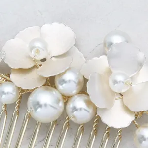 Primo piano dettagliato del pettine per capelli da sposa con fiori metallici e perle.