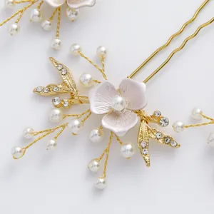 Primo piano dettaglio forcina da sposa con perle e fiore rosa. Elegante accessorio dorato.