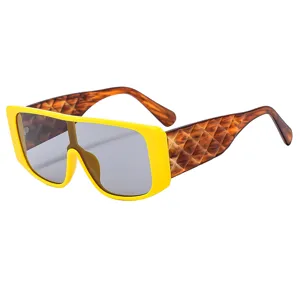 Occhiali da sole oversize con montatura gialla e stanghette larghe intrecciate marroni