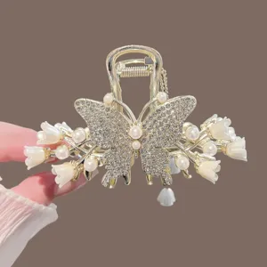 Élégante pince à cheveux muguet avec strass, perles et pompon pour coiffure femme.