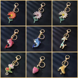 Detailed view showing multiple cute rhinestone keychain designs including flowers, dolphins, and strawberry.