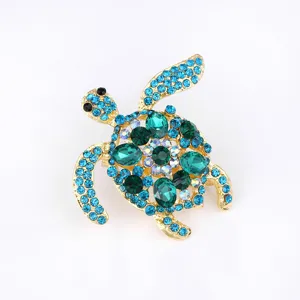 Close-up of a stunning rhinestone turtle brooch pin with blue and green crystals on gold.