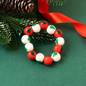 Close-up detail of Christmas wooden bead bracelet with red white beads and green tree print.