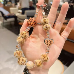 Colgante de teléfono con cuentas de leopardo y pompón esponjoso con detalle de corazón.