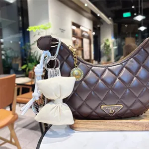 Quilted brown PU leather hobo bag with white bow keychain and metal charm accessory for daily use