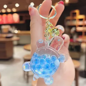 Dettaglio portachiavi tartaruga liquida trasparente, ciondolo blu glitterato per borse.