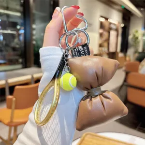 Cute PU leather bow and tennis racket keychain charm for handbag decoration and keys.