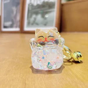Nahaufnahme des niedlichen transparenten Acryl-Glückskatzen-Schlüsselanhängers mit Flüssigkeit.