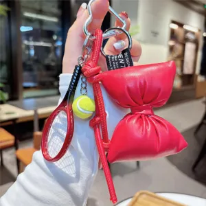 Red leather bow keychain charm featuring a cute miniature tennis racket accessory.