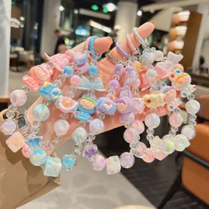 Closeup of colorful pastel beaded phone strap with cute cartoon dolls, sweet aesthetic style.