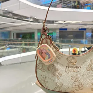 Vista dettagliata della borsa a spalla crema con motivo orso e mini portachiavi TV.