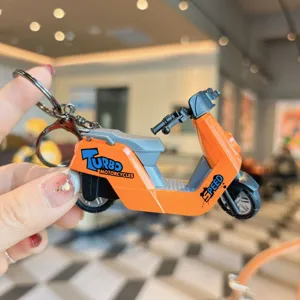 Close-up detail shot of an orange scooter motorcycle keychain pendant with alloy texture.