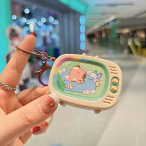 Primo piano dettagliato del simpatico portachiavi giocattolo capibara mini TV per borsa.