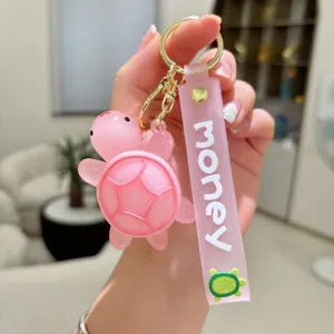 Detalle de llavero tortuga rosa, colgante de PVC con correa money para bolsos y llaves.