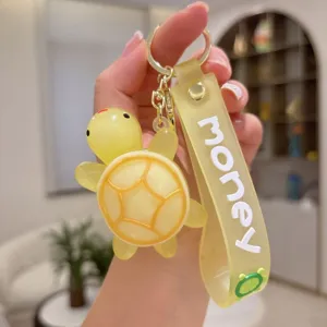 Detalle de llavero PVC de tortuga de dibujos animados, correa amarilla con texto y anillo.