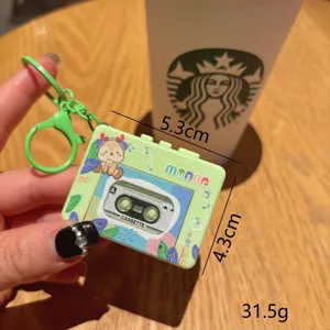 Close-up detail of green cassette tape keychain with cute deer graphic and music text.