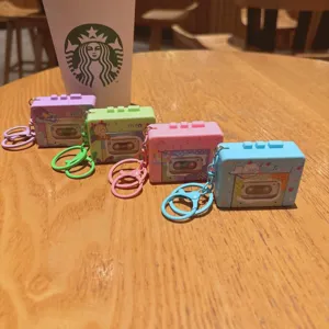 Colorful silicone cassette tape keychain detail view, cute retro bag pendant on wooden table.