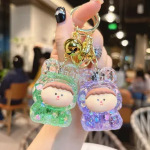 Detailed view of cute liquid quicksand acrylic keychain with green and purple cartoon figures.