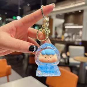 Close-up detail shot of cute blue quicksand liquid keychain pendant with gold metal hardware.
