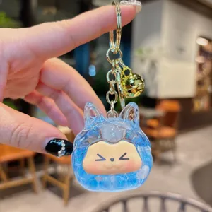Primo piano di un simpatico portachiavi liquido blu con anello dorato e ciondolo a campana.