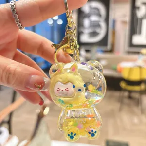 Closeup of transparent liquid glitter bear keychain with cute cartoon character inside gold ring.