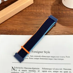 Dettaglio cinturino orologio in nylon con trama loop blu e arancione e connettore.