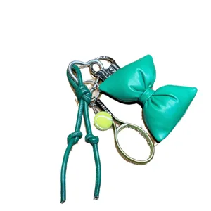Green PU leather bow keychain with tennis racket charm and metal heart buckle, stylish accessory.
