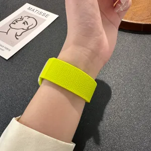 Nahaufnahme eines leuchtend gelben Silikonarmbands mit Litschistruktur am Handgelenk.