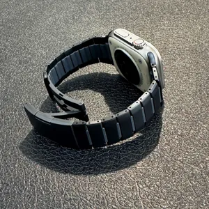 Detailed close-up view of curved metal watch band link showing precise construction and dark finish.