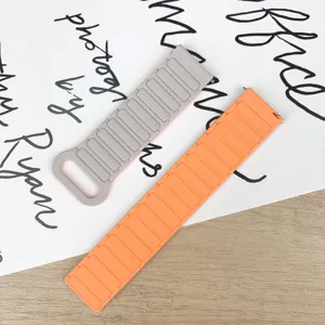 Silicone replacement watch band detail showing gray and orange colors on flat lay background.