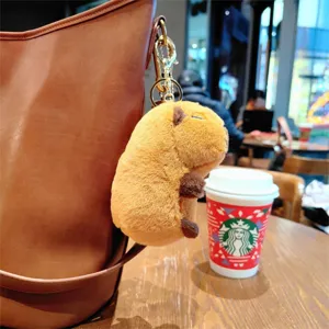 Cute capybara plush keychain soft animal toy dangling from leather bag aesthetic cafe charm
