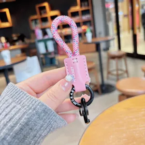 Detaillierte Nahaufnahme des rosa geflochtenen PU-Leder-Schlüsselanhängers mit schwarzer Metallbeschlag.