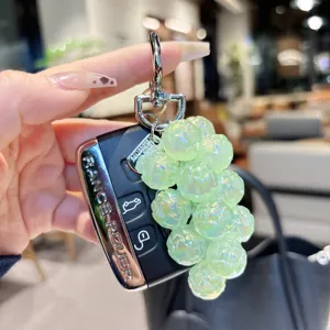 Detailed view of the sparkling acrylic grape charm keychain attached to a luxury car key.