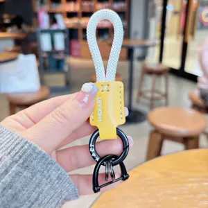 Detailaufnahme des geflochtenen Seil-Schlüsselanhängers mit gelbem Lederetikett und Metallring.
