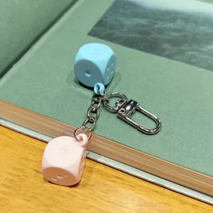 Close-up detail of the colorful macaron dice keychain pendant, showing fine metal clasp and links.