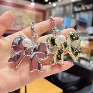 Exquisite bow keychain detail, cute pearl pendant phone charm and headphone accessory.