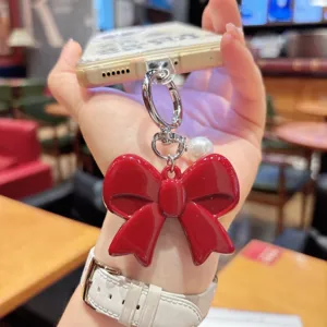 Exquisite red acrylic bow phone chain with pearl charm, stylish cute keychain accessory.