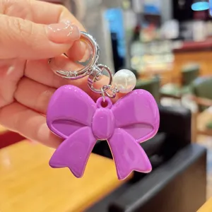 Purple bow keychain detail, cute acrylic bow with pearl accent, perfect accessory charm.