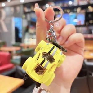 Close-up detail of yellow alloy sports car keychain pendant with wing and body style.