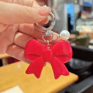 Red bow keychain with pearl pendant, cute acrylic bag charm and phone accessory for women.