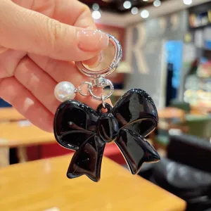 Korean style black bow keychain with white pearl pendant, cute acrylic bag charm accessory.