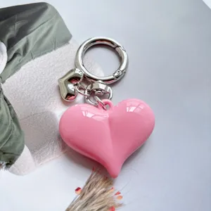 Close-up detail of a cute candy pink heart keychain with shiny silver metal ring and charm.