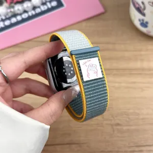 Close-up detail of nylon loop watch band with cute woven patch and vibrant yellow border.