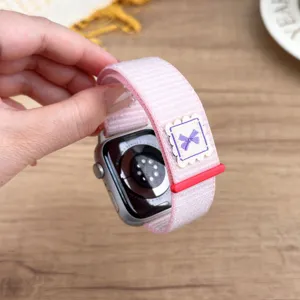 Pink nylon loop watch strap with purple bow and red buckle for apple watch replacement.