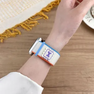 Close-up detail of woven nylon loop watch strap featuring cute bow ribbon and blue buckle.