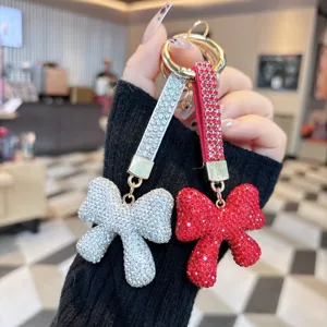 Rhinestone bow keychain detail showing sparkling crystal charms on double straps with gold ring.