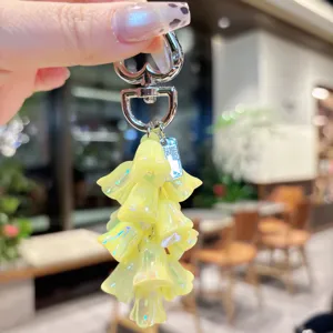 Dettaglio del portachiavi con mughetto giallo iridescente e ciondolo in metallo lucido.