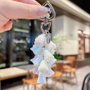Dettaglio in primo piano del portachiavi con mughetto iridescente e fiori perlati lucidi.